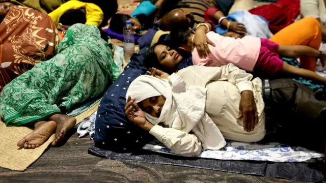 समुद्री आँधीका कारण  रेलसेवा स्थगित भएपछि एउटा स्टेशनमा आराम गर्दै यात्रुहरू