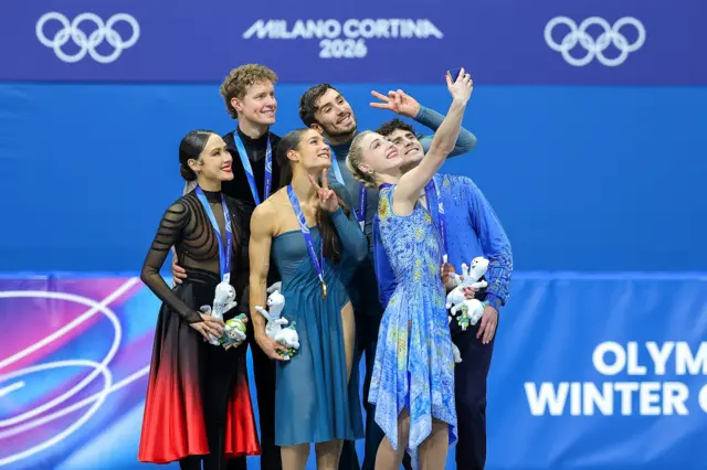 Фигуристы сборных Франции, США и Канады, завоевавшие медали в танцах на льду, делают селфи во время церемонии награждения в Милане