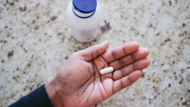 Pílula branca na mão de uma pessoa