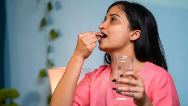 టాబ్లెట్ వేసుకుంటున్న యువతి