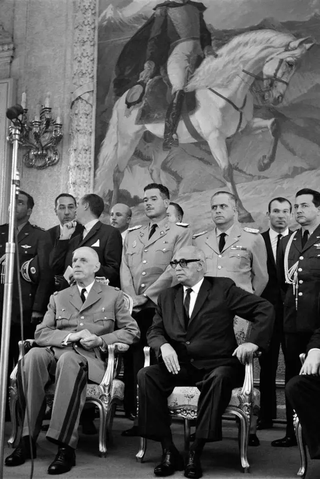 Charles de Gaulle, presidente de Francia, sentado al lado del presidente de Venezuela, Raúl Leoni, con otros funcionarios y con un cuadro de Simón Bolívar en el fondo