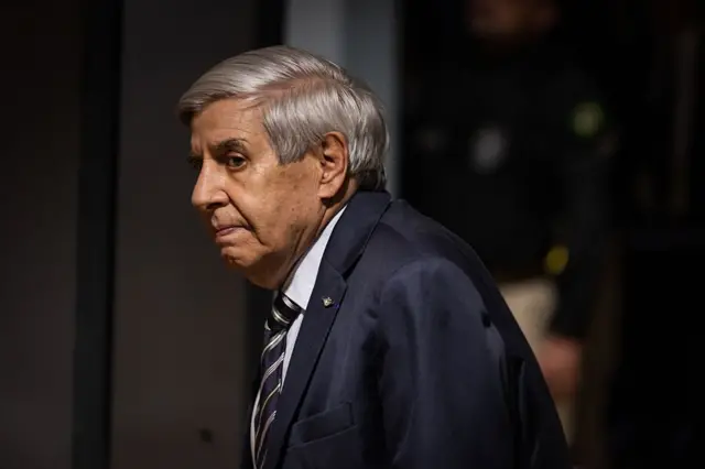 Heleno com olhar compenetrado, em pé, de perfil