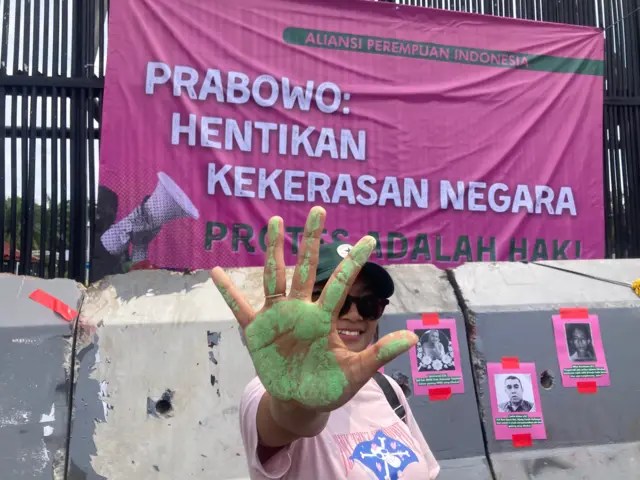 Salah seorang pengunjuk rasa menunjukkan tangan yang sudah dilumuri cat hijau sebagai tanpa pernyataan sikap mengecam kekerasan negara saat demonstrasi di depan gedung DPR pada Rabu (3/9).