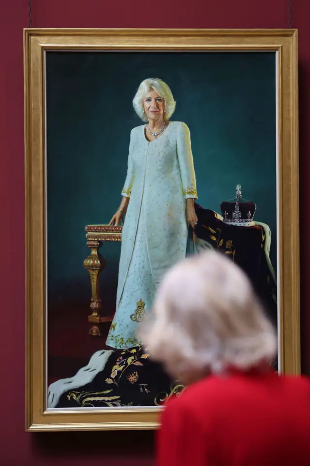Королева смотрит на свой портрет на стене 