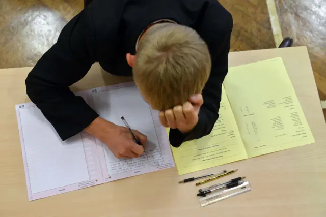 Дечак се држи за главу и пише на часу