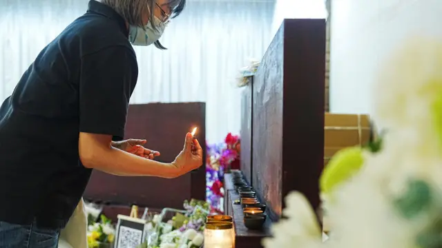 2025年12月2日，一名女子在九龍殯儀館點燃蠟燭，悼念香港大埔宏福苑火災中的罹難者。