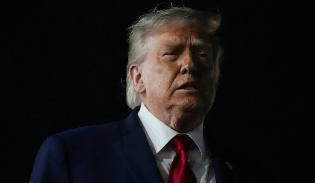 Donald Trump karanlık bir havada, bir yere bakıyor. Omuzundan üstünü görüyoruz.