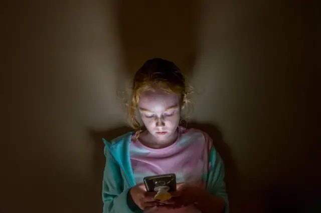 genç bir kız odasında telefon bakıyor