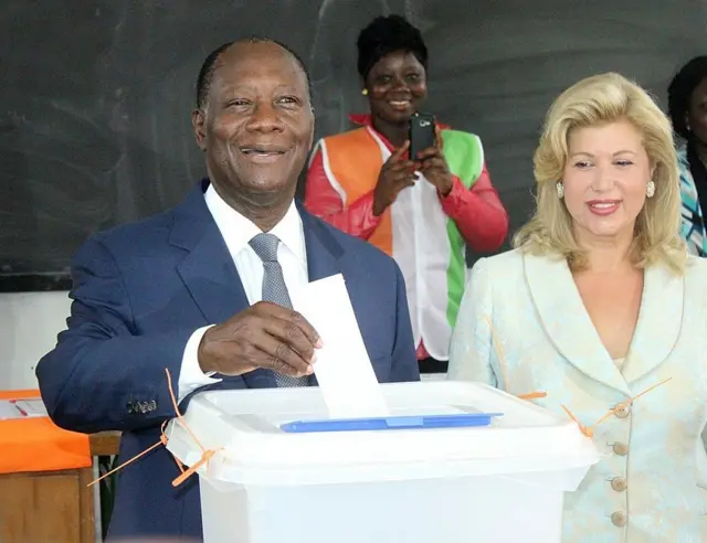 Le président Alassane Ouattara vote lors de la présidentielle de 2015, on aperàoit son épouse derrière lui. 