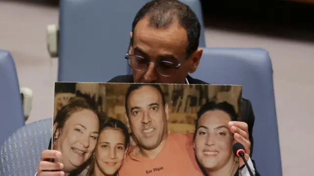 Eli Sharabi, a former Israeli hostage released by Hamas in Gaza last month, holds of a photograph of his wife and two daughters killed by Hamas, as he addresses a meeting of the United Nations Security Council 