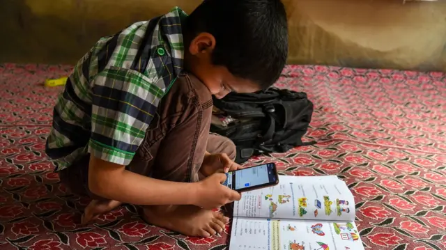 Un garçon manipulant un smartphone.