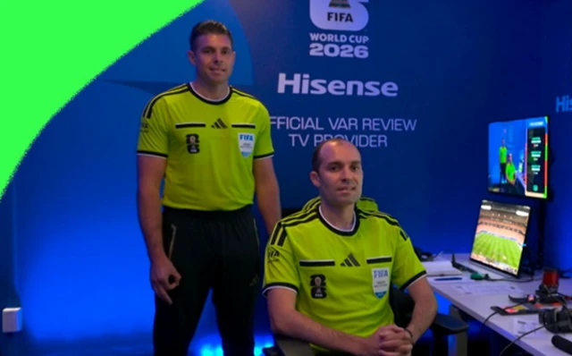 O árbitro Shaun Evans, à esquerda, faz com as mãos um OK de cabeça para baixo no centro de arbitragem da Fifa