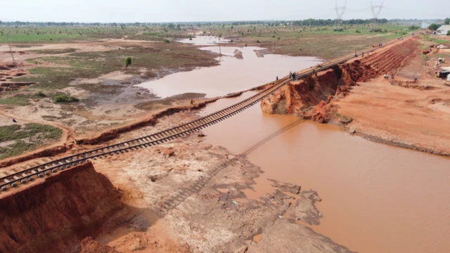 Road cut off by di flood, clay dey show wit train track wey dey hang