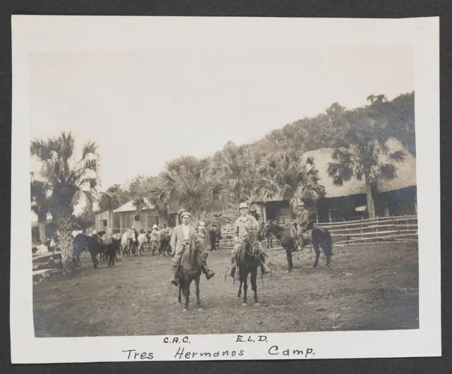 Los tres hombres a caballo en un lugar con palmeras y chozas