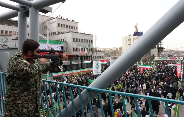 muškarac u maskirnoj uniformi sa snajperom nagleda proslavu 47. godine Islamske Republike Iran u Teheranu