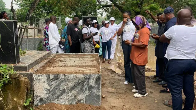 Pipo wear different colour of c;lothes stand around grave.