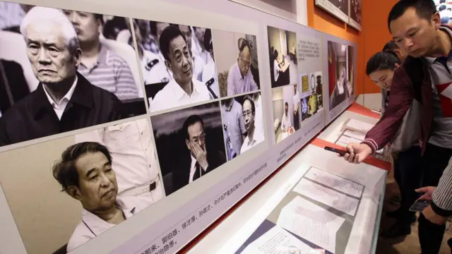 Visitors read the statements of repentance written by some of the fallen top corrupted officials, while the pictures of six highest ranking corrupted officials are displayed, (from upper left to right) Zhou Yongkang, Bo Xilai, Guo Boxing, Xu Caihou, Sun Zhengcai, and Ling Jihua