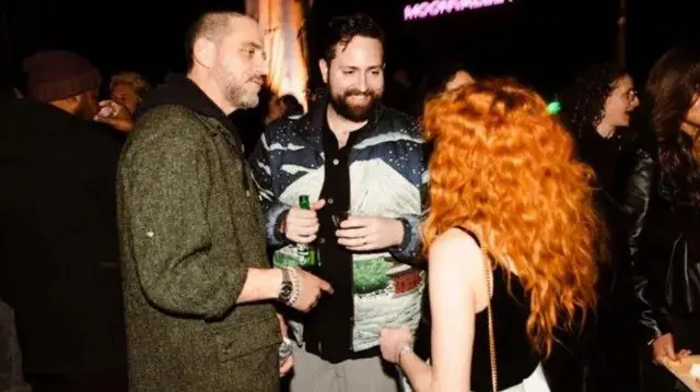 Três pessoas conversam em uma festa