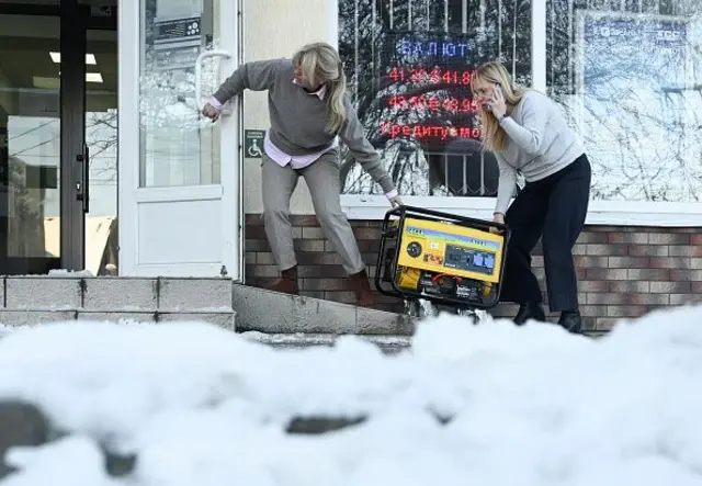 Двою жінок тягнуть генератор до крамниці на тлі снігу