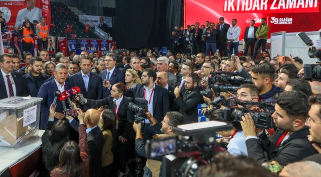 Özgür Özel sandık başında oy verdikten sonra gazetecilere konuşuyor. Yanında ve etrafında çok sayıda partili ve gazeteci var.