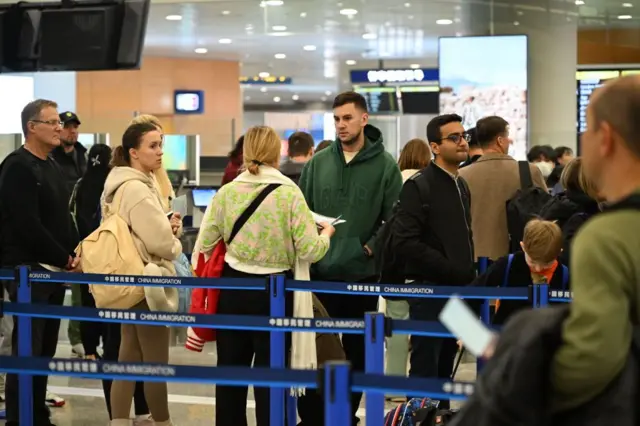 চীনের ইমিগ্রেশনের লাইনে দাঁড়িয়ে আছেন বিভিন্ন জাতিয়তার বেশ কয়েকজন মানুষ