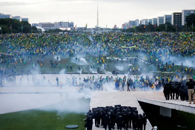 Multidão na Praça dos Três Poderes; é possível ver fumaça e alguns policiaismonte carlos aposta jogo de futebolformação