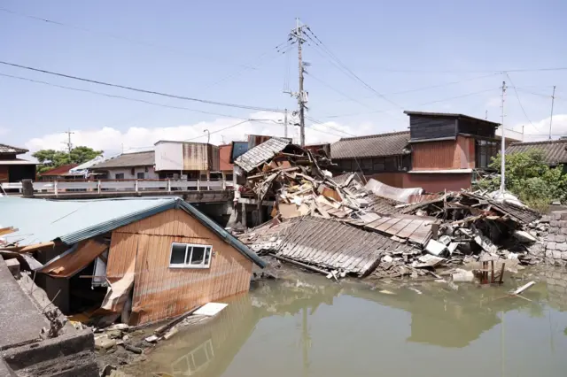 地震で倒壊した家屋の一部が、濁った川に落下している
