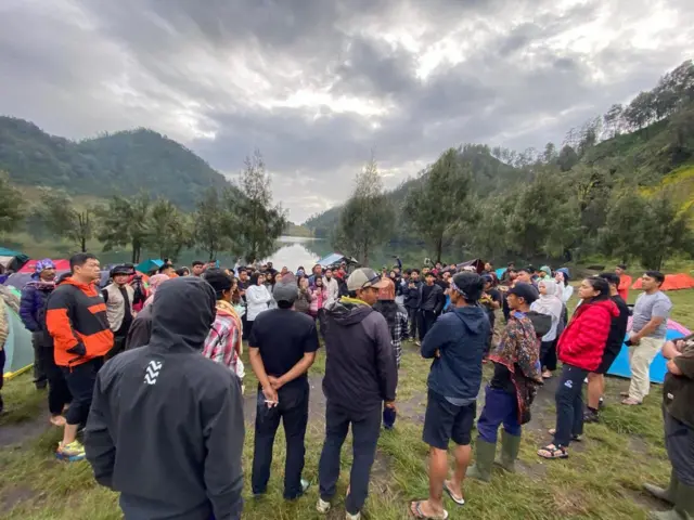 Sekelompok orang sedang berkumpul di area perkemahan.