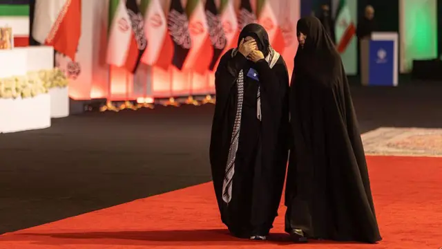امرأة تغطي وجهها أثناء مرورها أمام توابيت تضم جثمان المرشد الأعلى الإيراني الراحل، آية الله علي خامنئي، وأفراداً من عائلته، في مصلى الإمام الخميني الكبير في طهران، إيران، في 3 يوليو/تموز 2026.