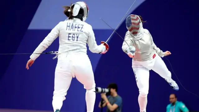 Nada Hafez wo mu Misiri (i bubamfu) aboneka mu mugongo ariko arahiganwa n'inkota na Elizabeth Tartakovsky (i buryo) wa Reta Zunze Ubumwe za Amerika mu rukino rwa fencing mu nkino Olympic z'i Paris mu 2024
