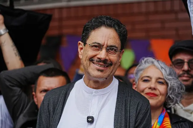 Iván Cepeda, candidato del partido Pacto Histórico, habla con los medios tras emitir su voto en las elecciones presidenciales del 31 de mayo de 2026 en Bogotá, Colombia. Sonríe a la cámara y lleva una camisa blanca y un suéter gris. 