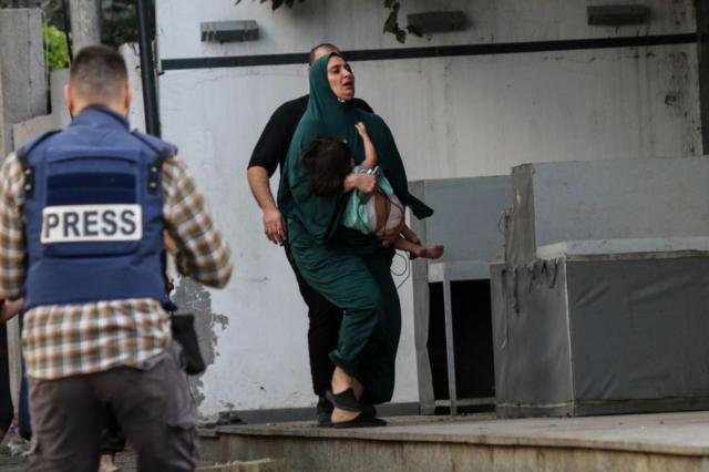 Una mujer palestina carga con un niño mientras huye de su casa en la ciudad de Gaza este 9 de octubre.