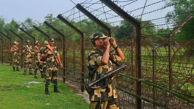 কয়েকজন বিএসএফ সদস্য চোখে দুরবীন লাগিয়ে সীমান্তের কাটাতারের বেড়ার বাইরে থেকে নজরদারি করছেন