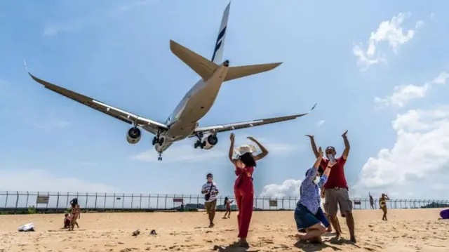 Tourists celebrate as a plane lands at Phuket airport. The Air India plane was on a flight from Phuket to Delhi
