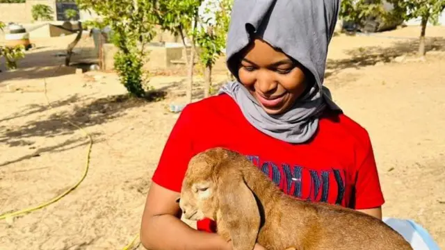 La jeune entrepreneur Madipa tenant une brebis entre ses mains.