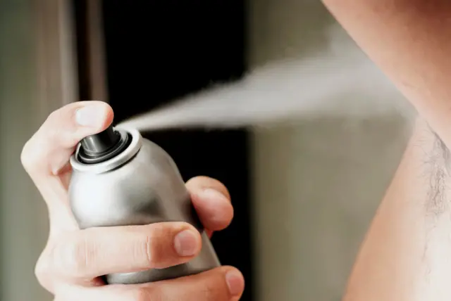 Birisi kolunun altına deodorant sıkıyor.