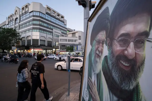جوانان بدون حجاب در خیابان از کنار عکس خامنه‌ای عبور می‌کنند