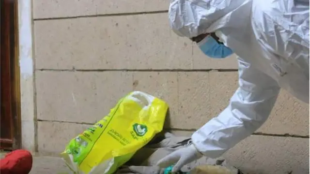 One investigator dey pick im way through di many belongings pipo leave behind for di site