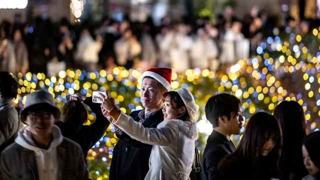Pessoas comemorando o Natal ao ar livre, algumas tirando fotografias