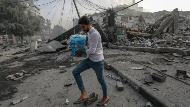 رجل فلسطيني يمر أمام "برج وطن" المدمر في مدينة غزة، 08 أكتوبر/تشرين الأول 2023.