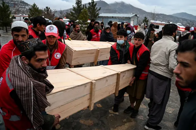 د سرې میاشتې ټولنې ګڼ رضاکاران برېښي چې تابوتونه لېږدوي. شاوخوا ګڼ کسان ورټول دي.