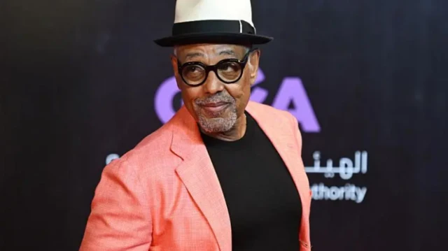 الممثل الأمريكي جيانكارلو إسبوزيتو يرتدي سترة وردية وخلفه شعار الهيئة العامة للترفيه في السعودية