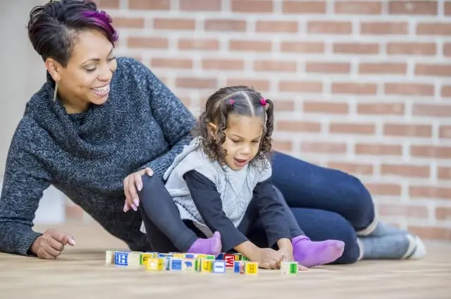 Uma mãe brincando com a filha no chão