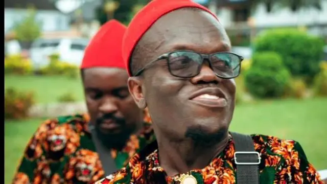 Victor Nwaogu a ma ama dịka 'Nkubi ebe o yi akwa isiagụ na okpu mmee mmee dịka ọ na-achị ọchị. Onye ọzọ jikwa akwa isiagụ nọ ọdụ n'azụ ya