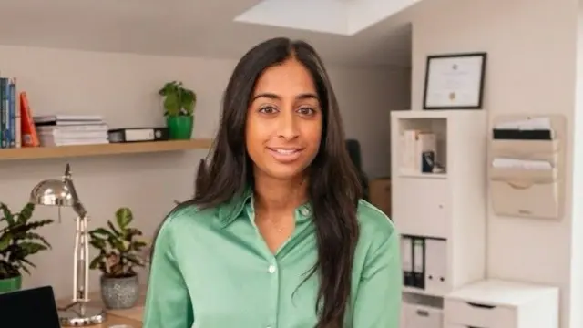 Anjali Malik has long black hair and wears a green shirt