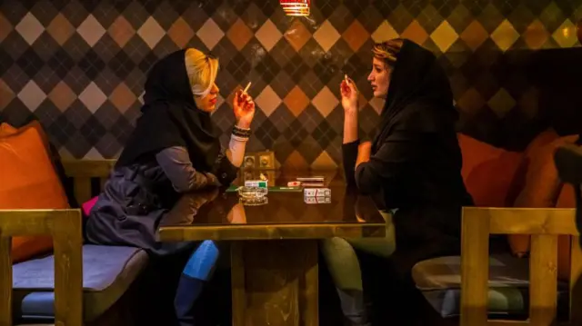 دختران جوان در یک کافه سیگار می کشند. تهران، ایران.