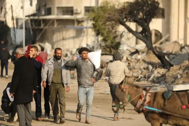 فلسطيني يتمكن من الحصول على كيس طحين من شاحنة مساعدات وصلت إلى شارع الرشيد غرب مدينة غزة شمالي القطاع في 28 فبراير/شباط 2024