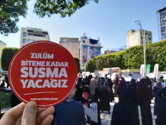 Furkan Vakfı'nın düzenlediği bir eylemde bir kişi elinde "Zulüm bitene kadar susmayacağız" yazan bir kağıt tutuyor