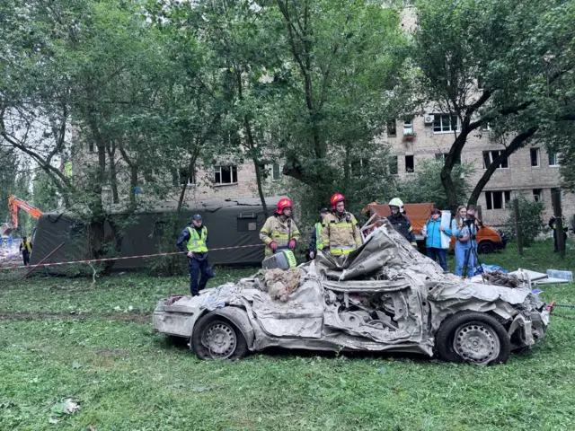 Рятувальники забирають пошкоджені авто від обваленого будинку 