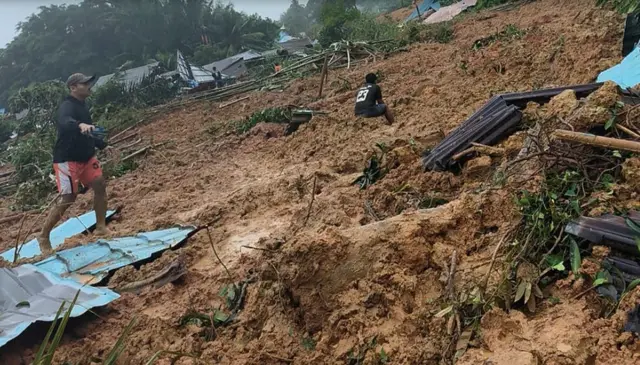 Seorang warga berjalan di lokasi kejadian tanah longsor di Kecamatan Serasan, Kabupaten Natuna, Kepulauan Riau, Senin (6/3). 